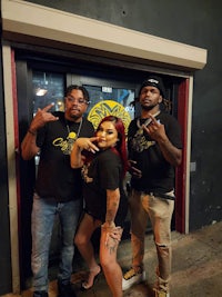 three people posing for a picture in front of a door